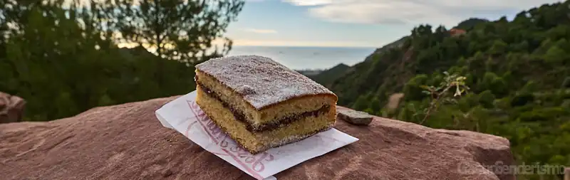 Porción de coca malfeta tradicional rellena de chocolate sobre una roca con vistas al mar en Benicàssim, Castellón