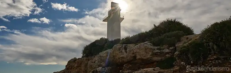 Faro de Irta a contraluz sobre acantilados rocosos en Alcossebre, Castellón
