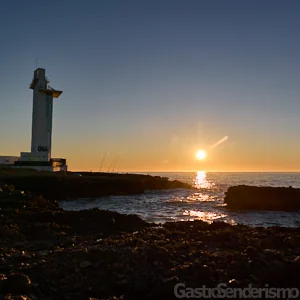 Faro de Irta al amanecer, con pescadores cerca, en Alcossebre, Castellón