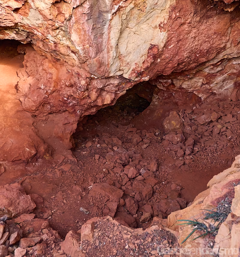 Vista del interior de una boca de extracción en la mina de ocre del Albir con rocas y suelo de color rojizo